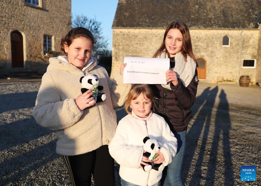 (Da sinistra a destra) Anaelle, Camille e Norah Marion, provenienti dalla Francia posano con un cartello sul quale è scritto "Insieme per un futuro condiviso", il motto ufficiale di Beijing 2022, a Meautis Manica Francia. (14 gennaio 2022-Xinhua/Gao Jing)