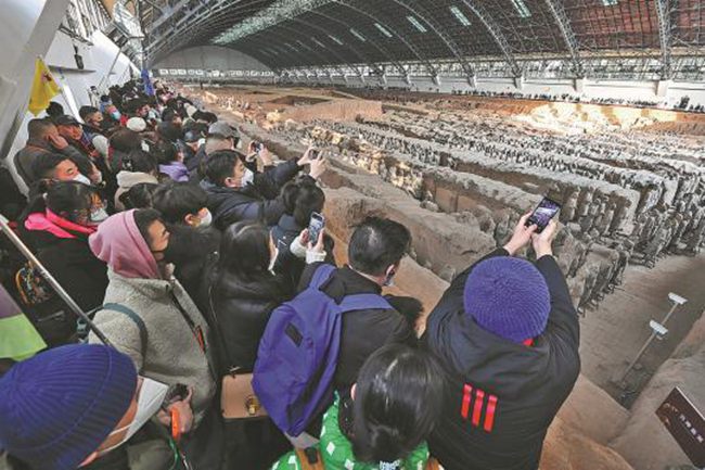 I turisti scattano foto mentre visitano i Guerrieri di Terracotta a Xi'an, nella provincia dello Shaanxi. Durante le vacanze della Festa di Primavera, il famoso sito storico ha attirato un gran numero di visitatori. (23 gennaio 2023 - Zhang Tianzhu/China Daily)