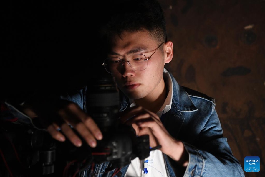 Xiong Yeteng, tecnico del team di conservazione digitale dell'Accademia di Dunhuang, si prepara l'attrezzatura per catturare immagini di murales in una delle Grotte di Mogao a Dunhuang, provincia del Gansu. (25 aprile 2023 - Xinhua/Fang Xin)