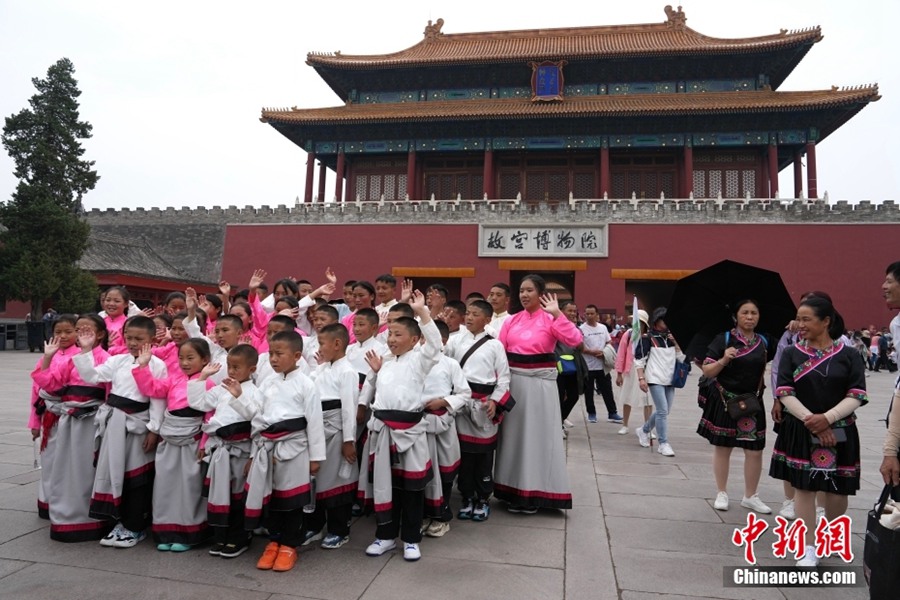 I ragazzi scattano una foto di gruppo davanti alla Porta Shenwu della Città Proibita, attirando l'attenzione di un gruppo di visitatori Mulao del Guangxi. (China News Service/Cui Nan)