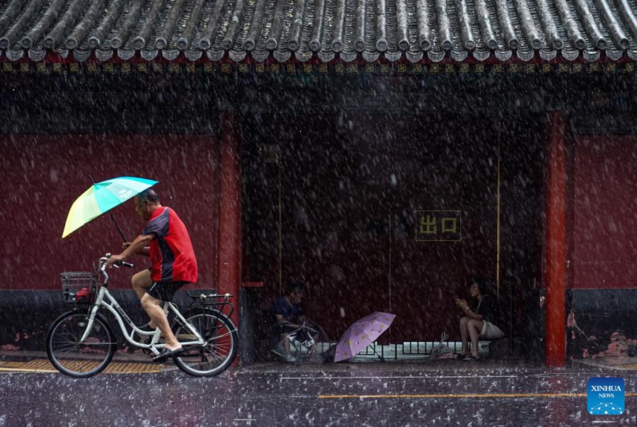 Un uomo va in bicicletta sotto la pioggia a Beijing. (30 luglio 2023 - Foto/Xinhua)