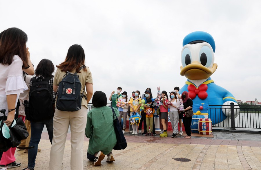 Turisti posano con un pupazzo gonfiabile di Paperino al Wishing Star Park del Disney Resort a Shanghai, nella Cina orientale. (10 giugno 2022 - Xinhua/Fang Zhe)