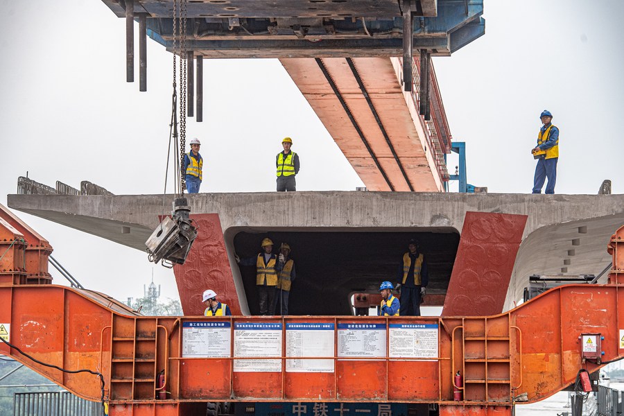 Addetti ai lavori installano una trave a cassone nel cantiere del grande ponte di Louwan, nella municipalità di Chongqing, lungo la ferrovia ad alta velocità Chongqing-Kunming, nel sud-ovest della Cina. (21 novembre 2023-Xinhua/Tang Yi)