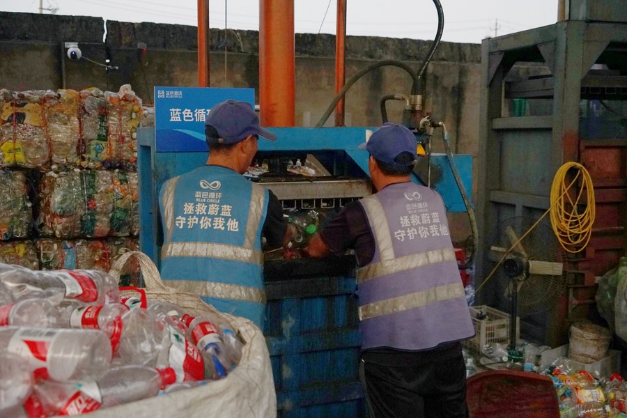 Operai comprimono bottiglie di plastica selezionate in un centro di riciclo nel distretto Jiaojiang di Taizhou, provincia dello Zhejiang. (17 ottobre 2023 - Xinhua/Lin Guangyao)