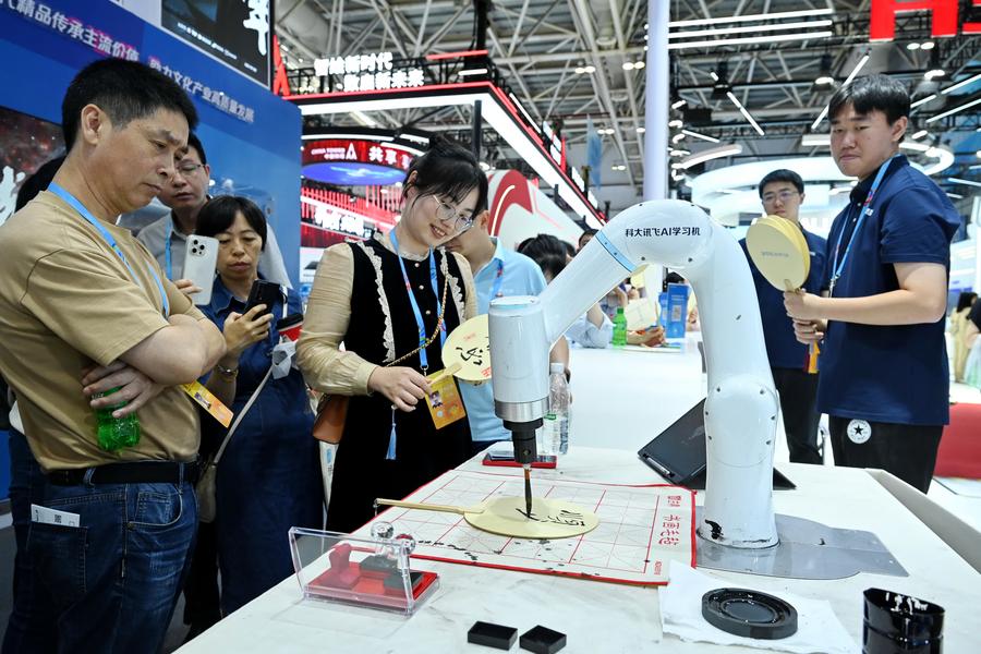 Le persone osservano un braccio robotico alimentato dall'intelligenza artificiale che scrive con un pennello nell'area di esperienza pratica del 7° Summit sulla Cina Digitale a Fuzhou, nella provincia del Fujian, nel sud-est della Cina. (24 maggio 2024 - Xinhua/Lin Shanchuan)