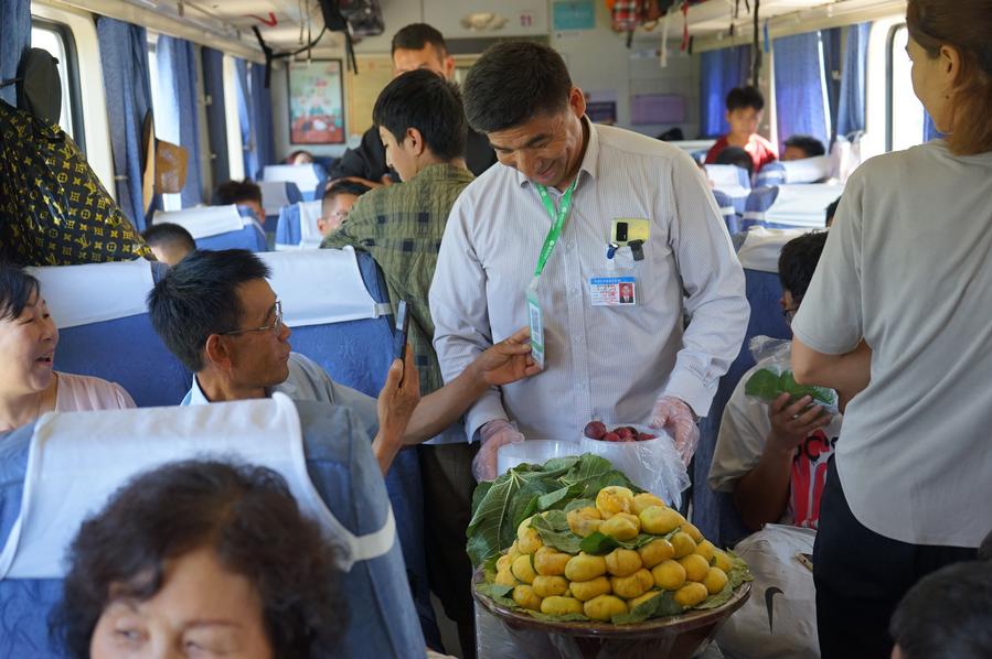 Un turista scansiona il codice QR per pagare i fichi acquistati dal venditore Yimamamat Saipar a bordo del treno n. 7557. (1 agosto 2024 - Xinhua/Jin Bowen)